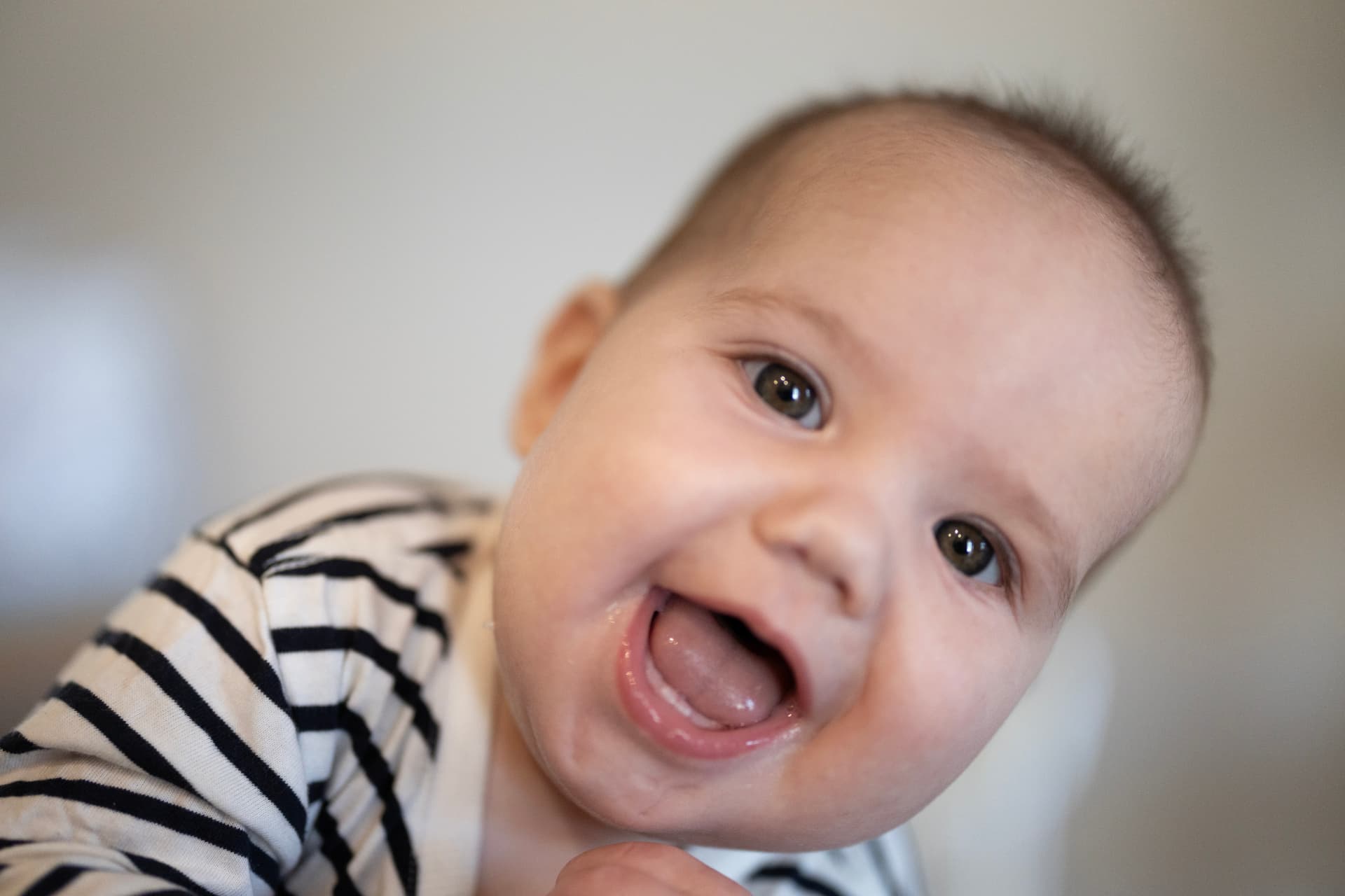 Smiling baby in a striped top photographed in a warm in-home studio