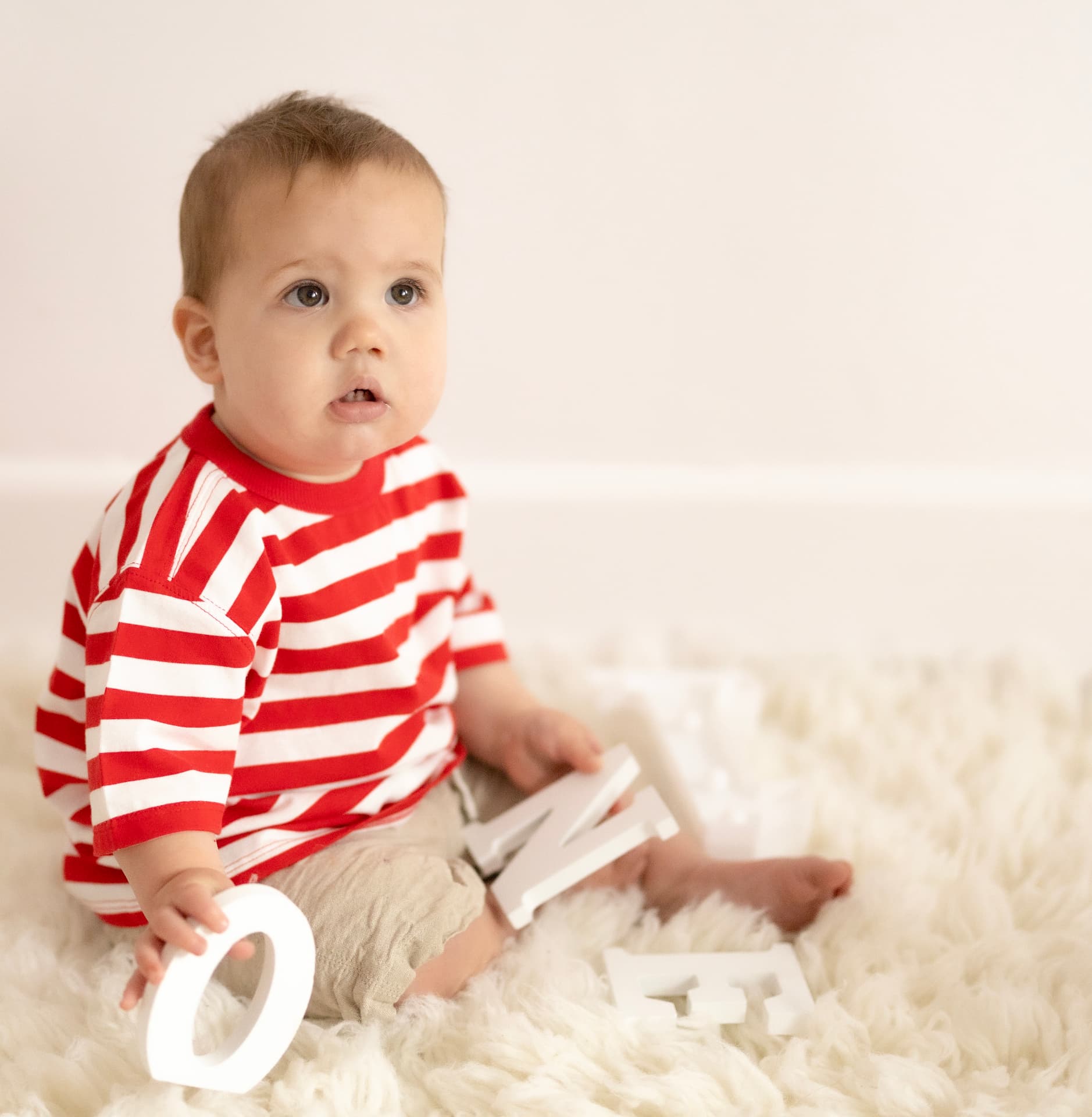 Toddler in a red striped top playing with wooden letters