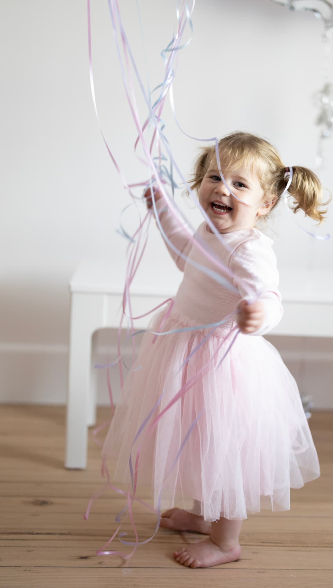 Young girl in a tulle dress playing with streaming ribbons